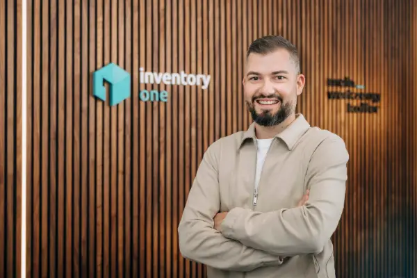 Christoph Winter, Geschäftsführer von Inventory ONE, mit verschränkten Armen vor der Holzwand im Büro