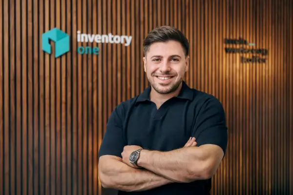Michael Reik, Geschäftsführer von Inventory ONE, mit verschränkten Armen vor der Holzwand im Büro