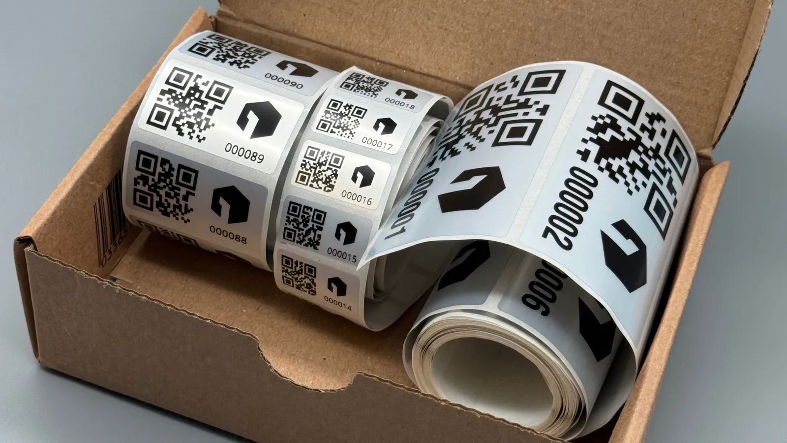 Rollen mit QR-Code-Etiketten in einem Versandkarton